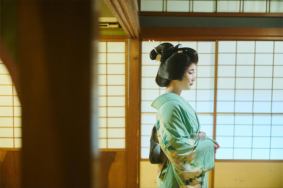 Maiko in a pink kimono interacting with a guest during a private cultural experience in Kyoto
